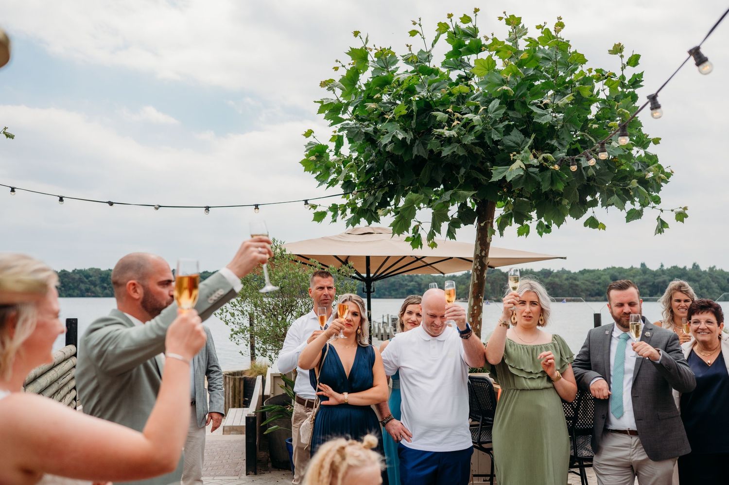 Gasten lachen en genieten van buitenreceptie, spontane bruidsfotografie IJM IJzereman Vught, Brabant.