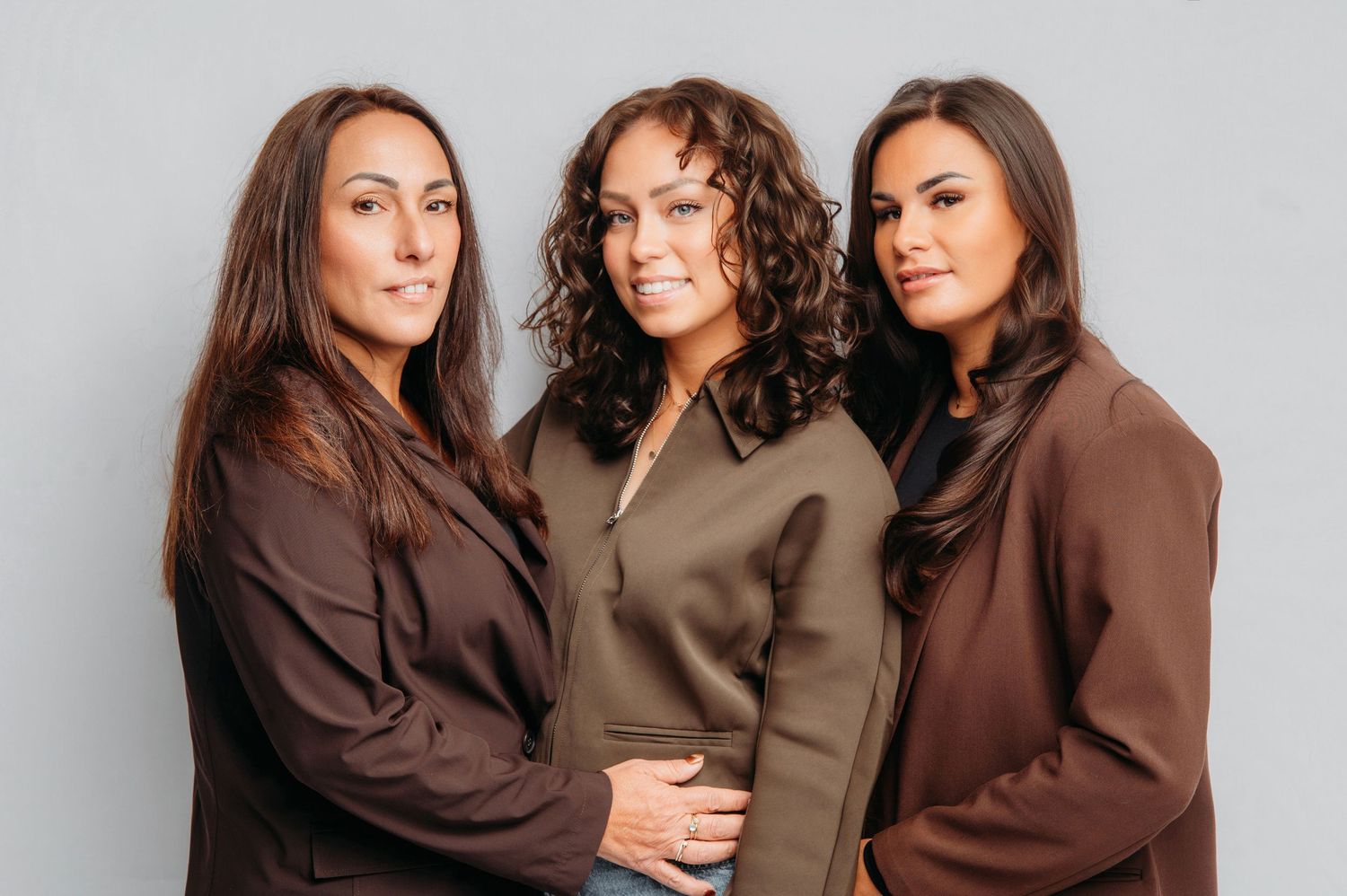 Drie vrouwen in bruin en beige omhelzen elkaar, portretfotografie Vught, Brabant.