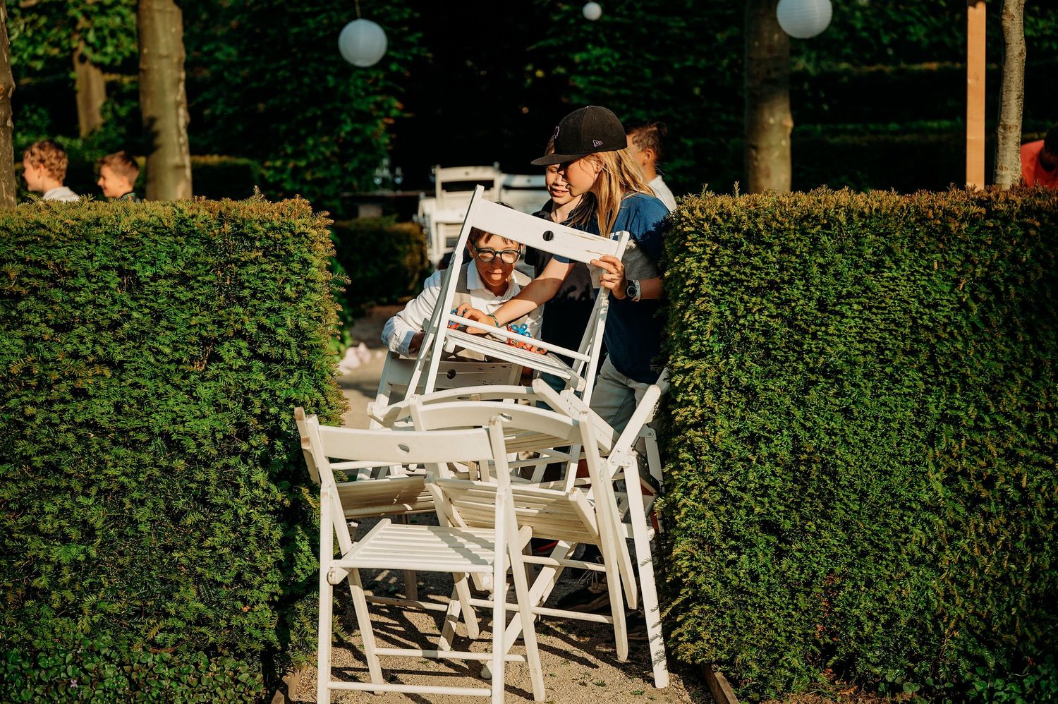 Witte tuinstoelen gerangschikt in rijen voor een buitenceremonie, bruiloftsfotografie Brabant.
