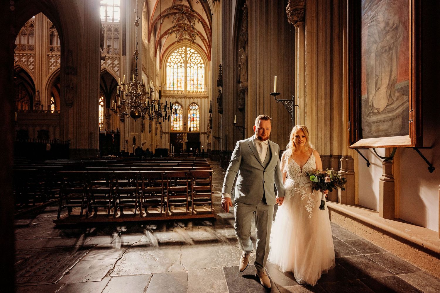 Bruidspaar in imposant kerkinterieur met glas in lood, romantische bruidsfotografie in Den Bosch en omgeving Brabant.
