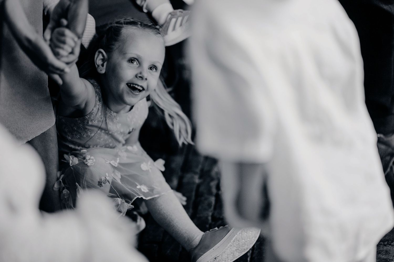 Black and white photo of a joyful young girl laughing at a wedding celebration.