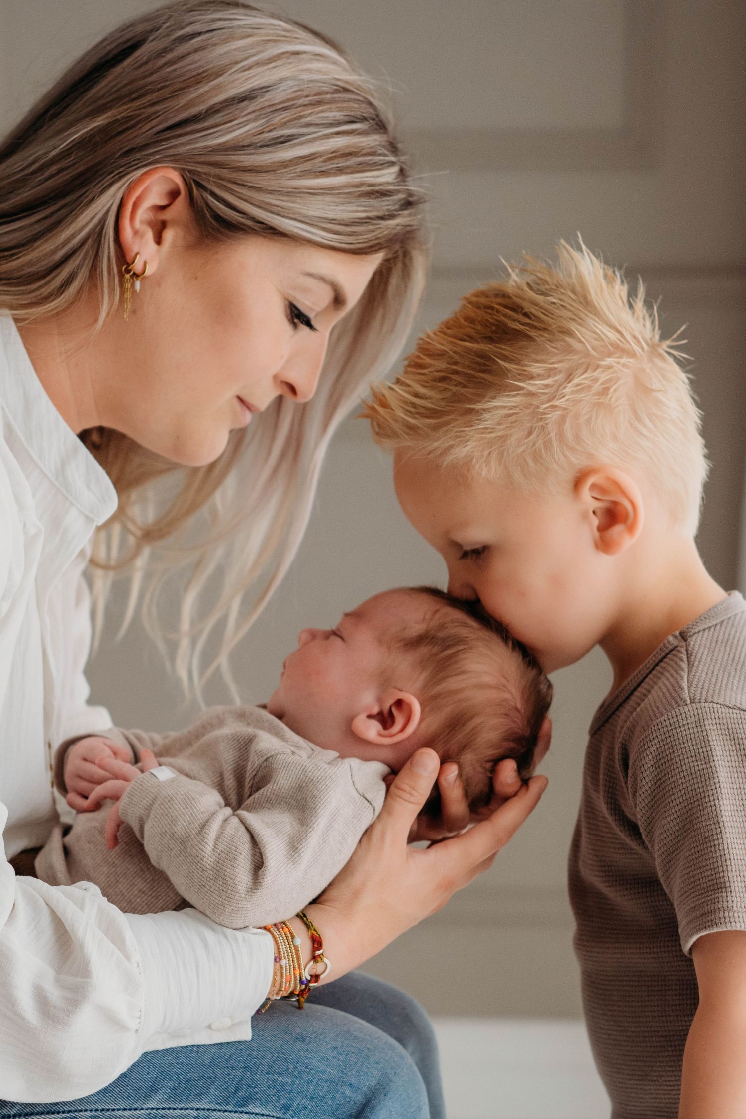 Slapende pasgeborene in perzikkleurige outfit op gestructureerde witte ondergrond, newbornfotografie Brabant