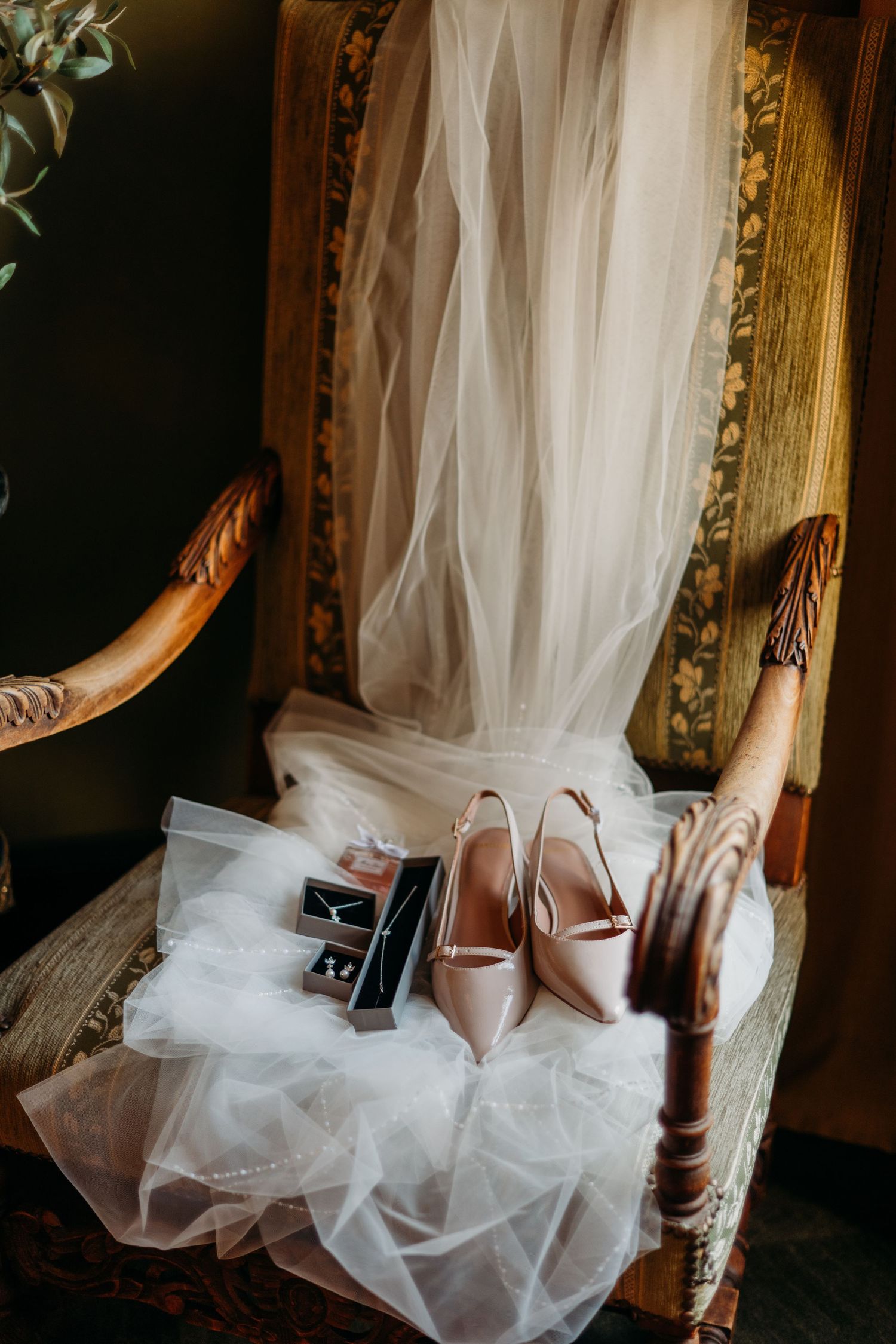 Elegante blush trouwschoenen op antieke stoel met vloeiende witte sluier, bruidsfotografie Noordbrabants Museum Den Bosch, Brabant.
