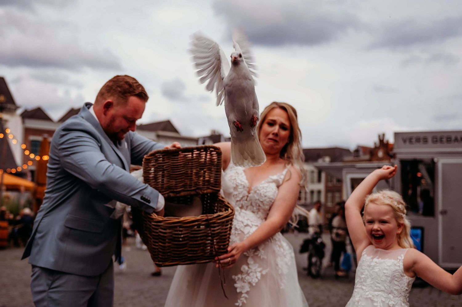 Bruidspaar en gasten met picknickmand in stadscentrum, spontane bruidsfotografie in Den Bosch en omgeving Brabant.