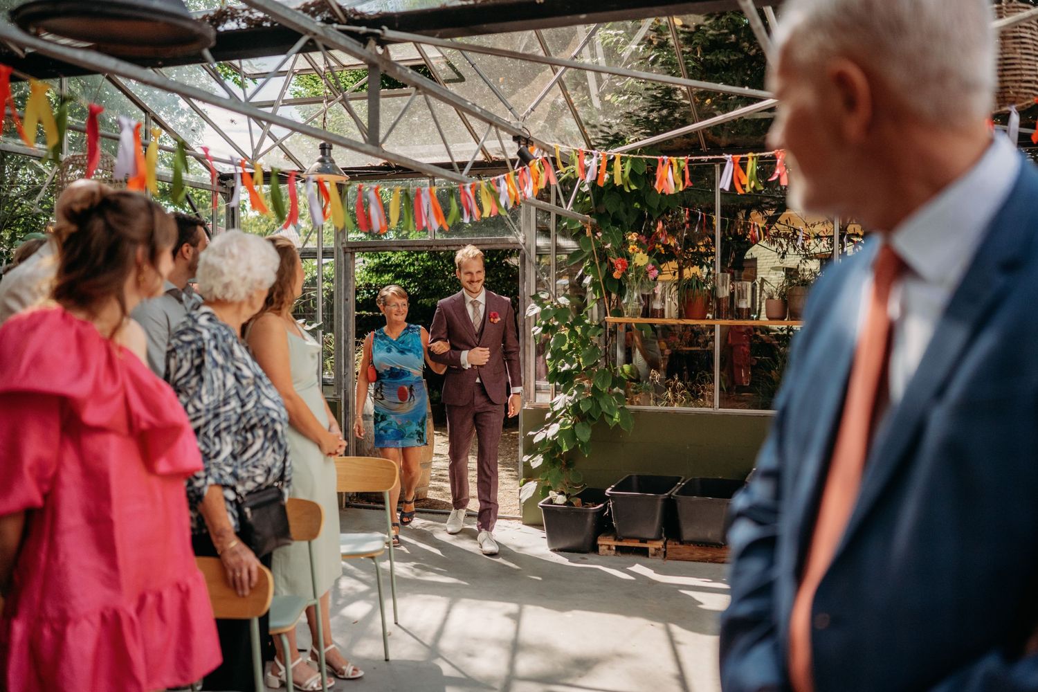 Colorful bunting decorates an outdoor market space with people gathered beneath a covered area.