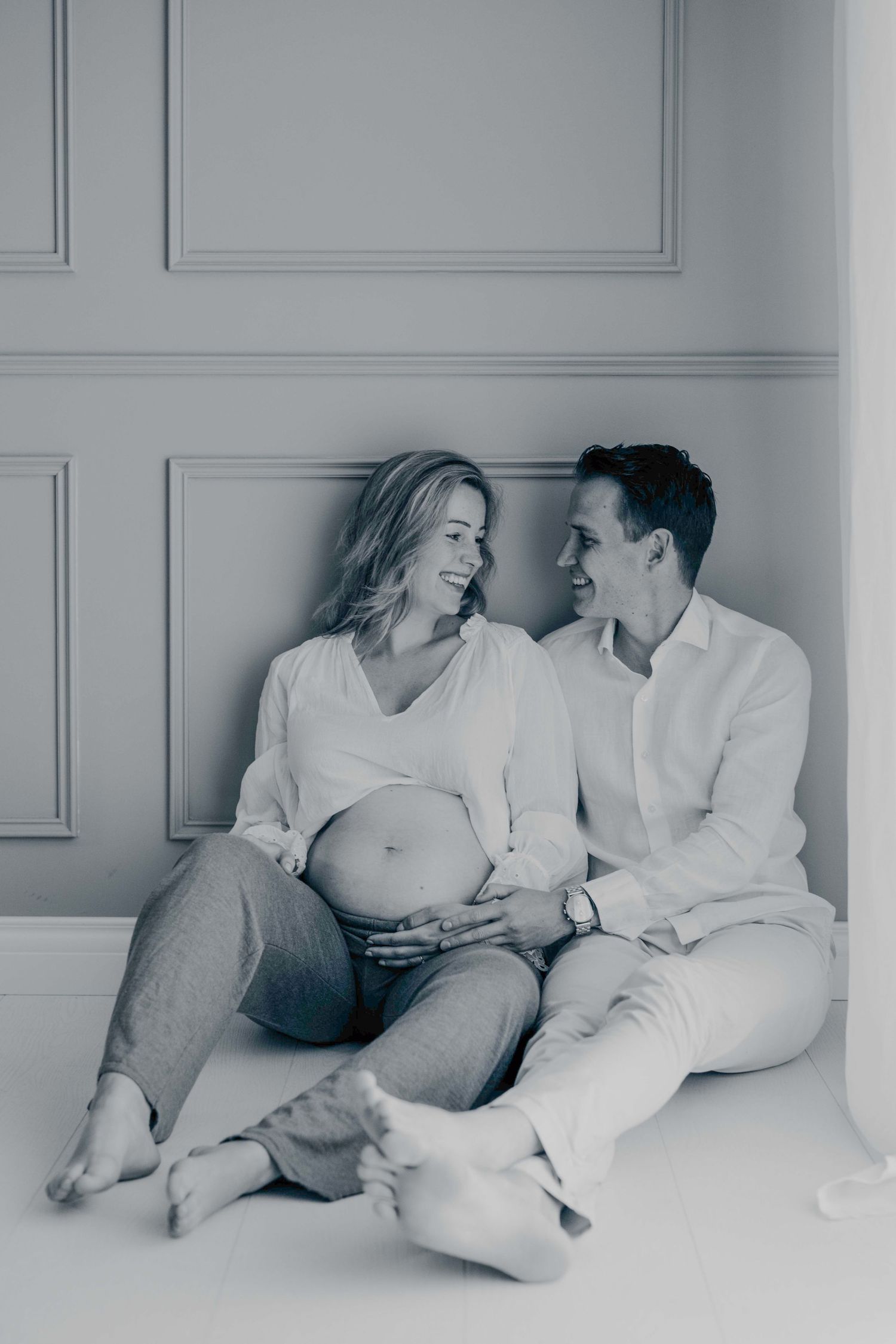Minimalistische koppelshoot met witte decoratie en intieme poses, zwangerschapsfotografie Brabant