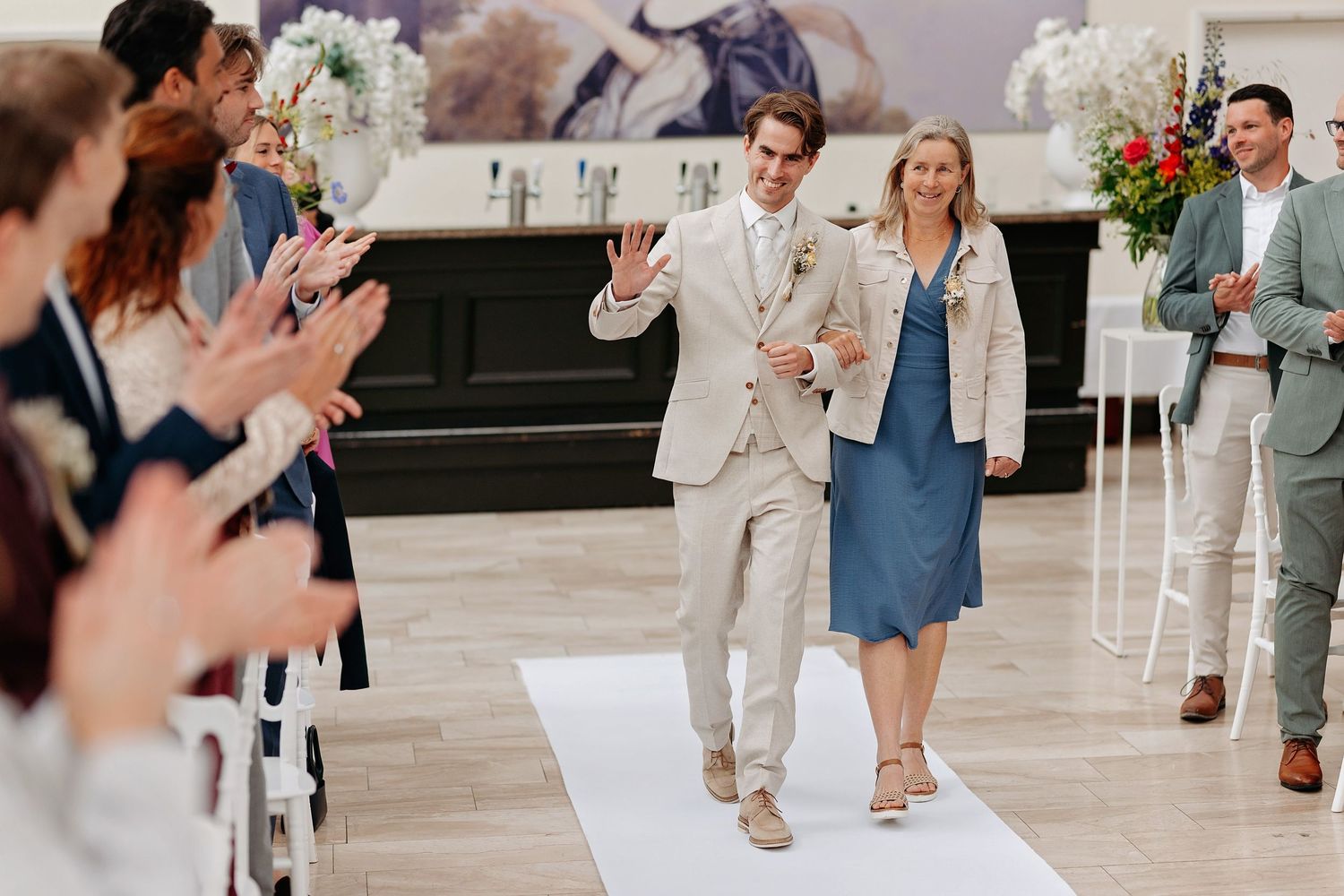 De bruidegom loopt samen met zijn moeder naar de ceremonie tijdens de trouwdag.