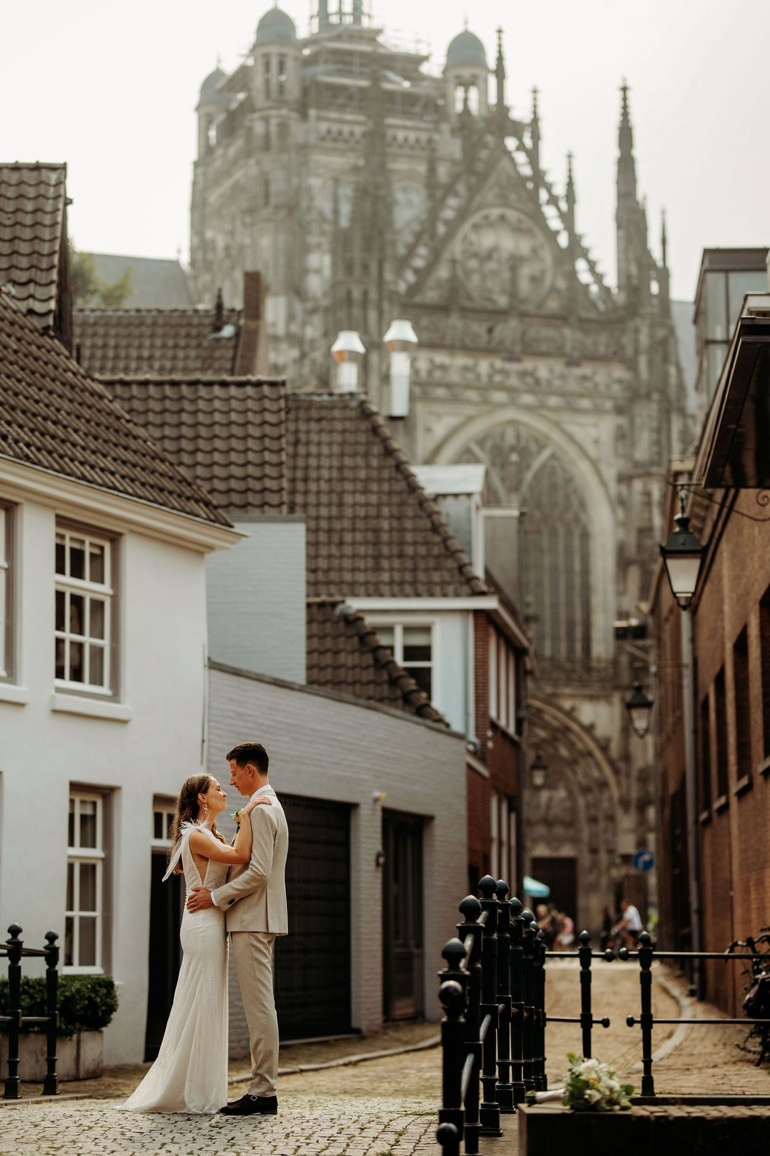 Bruidspaar op kasseien met de Sint Jan op achtergrond, romantische bruidsfotografie in Den Bosch en omgeving Brabant.