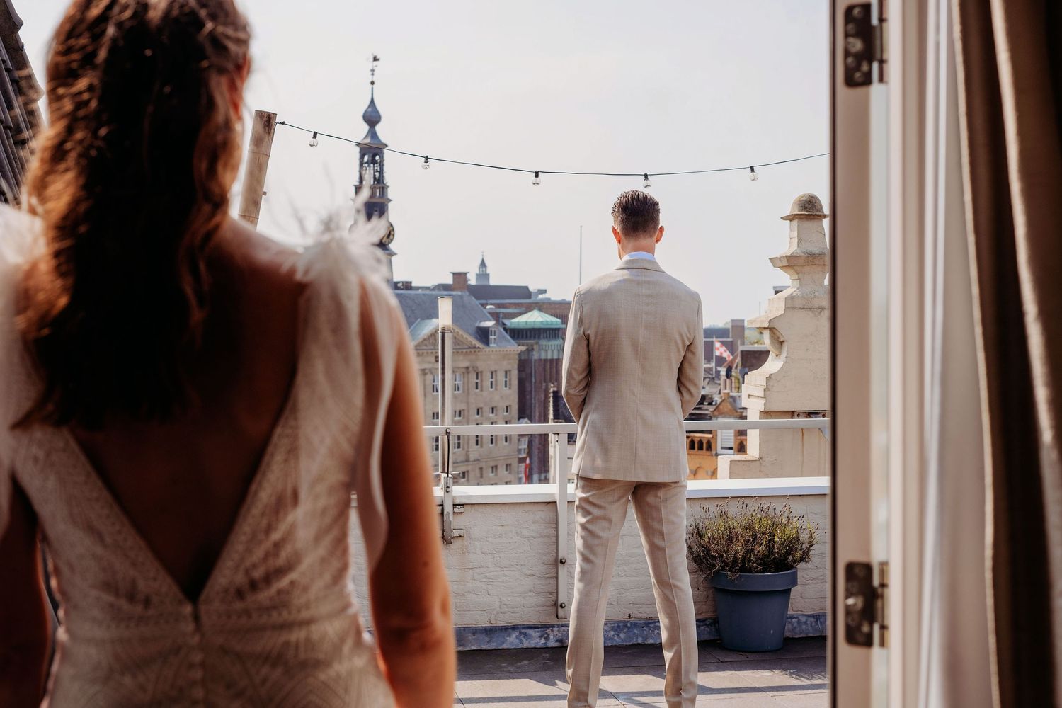 Silhouet van bruidspaar op balkon bij schemer met stadszicht, romantische bruidsfotografie in Den Bosch en omgeving Brabant.