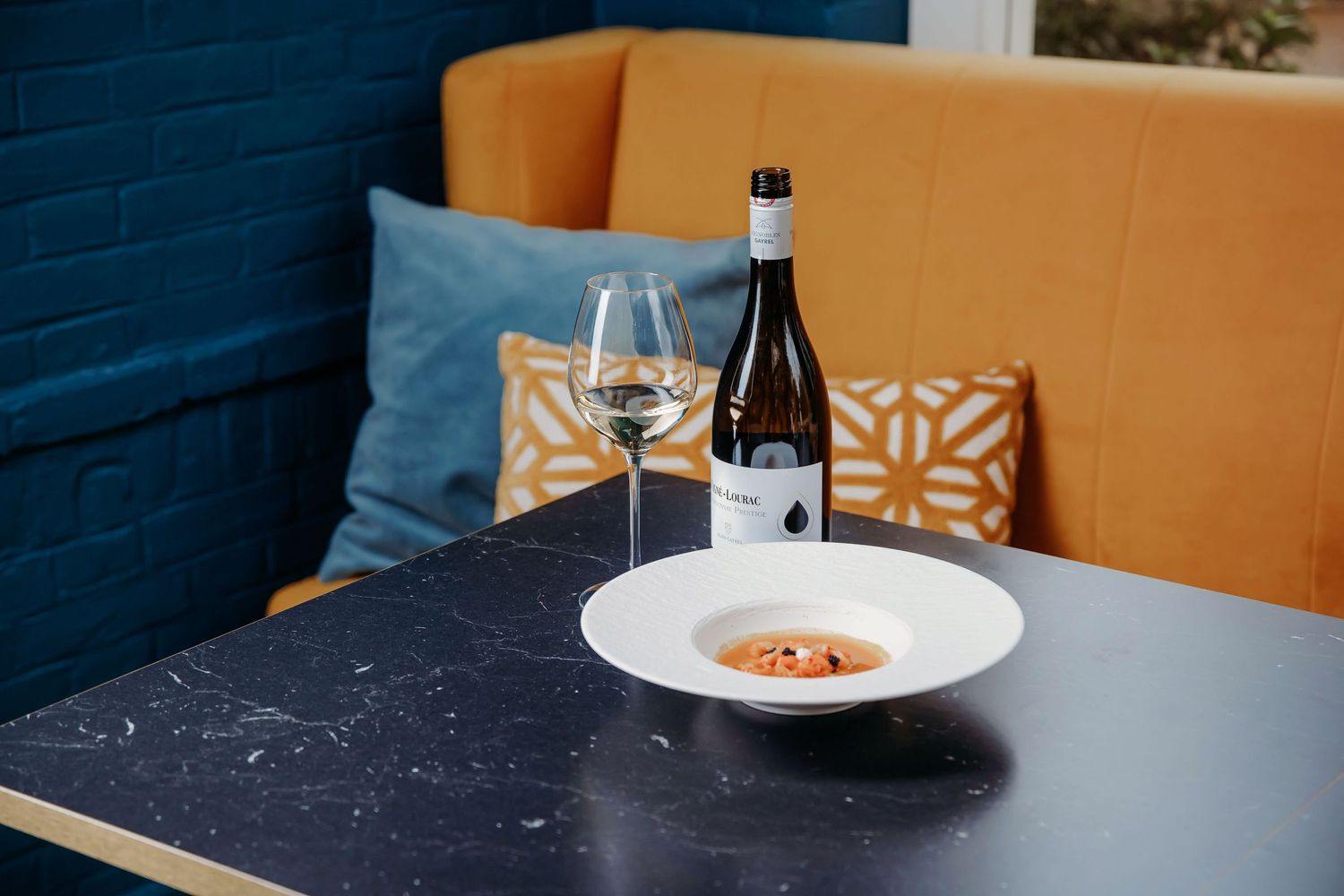 Restauranttafel met oranje zitbank en marineblauwe muurdecoratie, foodfotografie Brabant