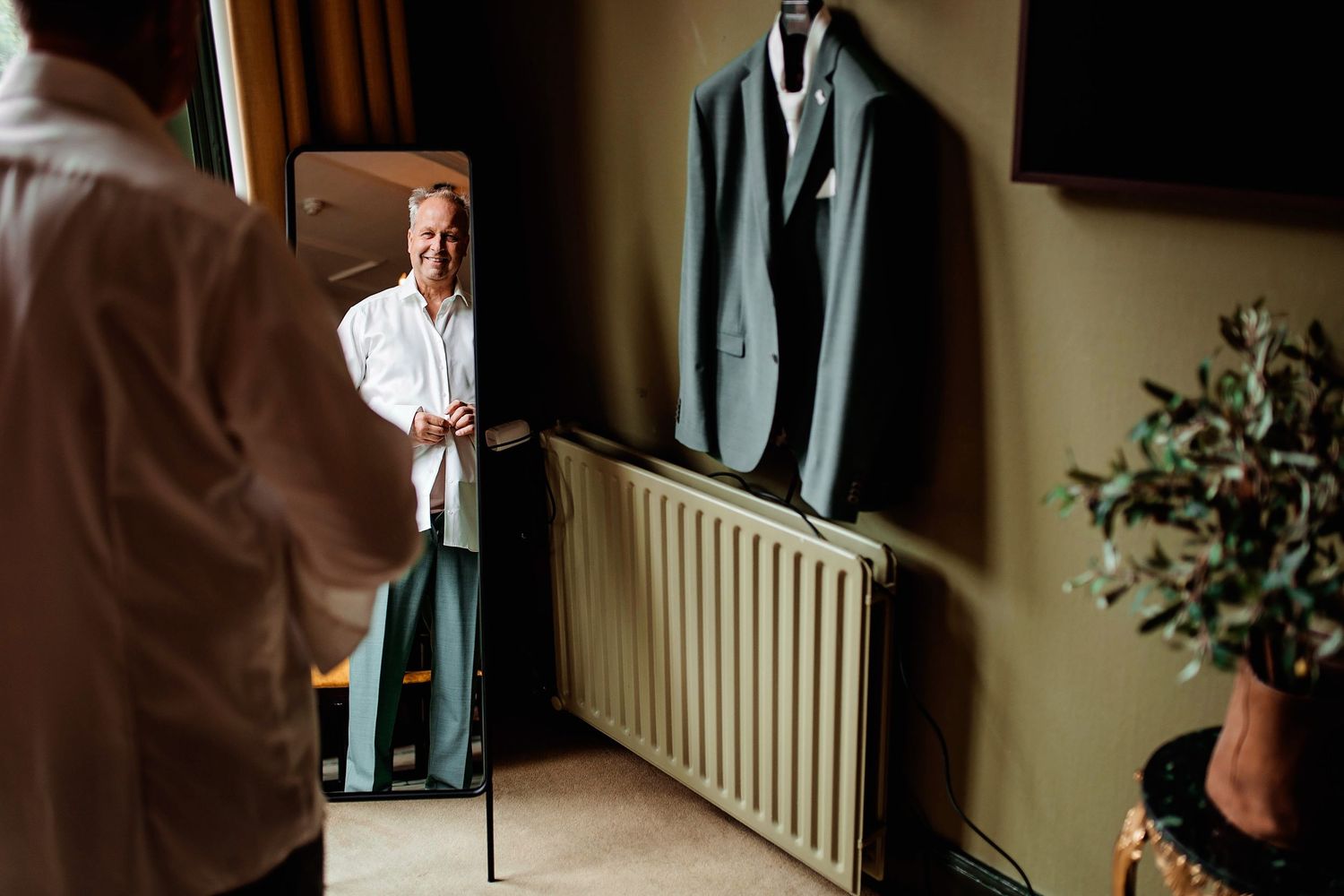 Persoon in wit shirt staat in gang met radiator en planten, portretfotografie Vught, Brabant.