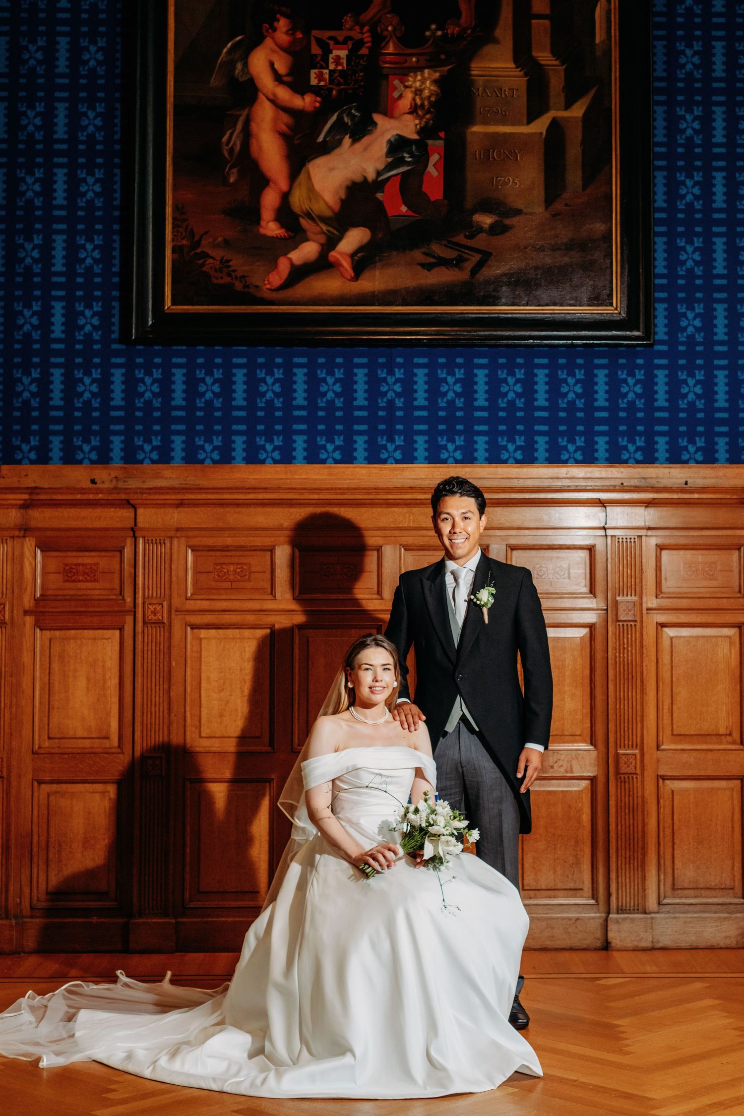 Elegante balzaal met houten panelen en blauwe muur, bruidspaar poseert op gepolijste vloer, bruidsfotografie Noordbrabants Museum Den Bosch,