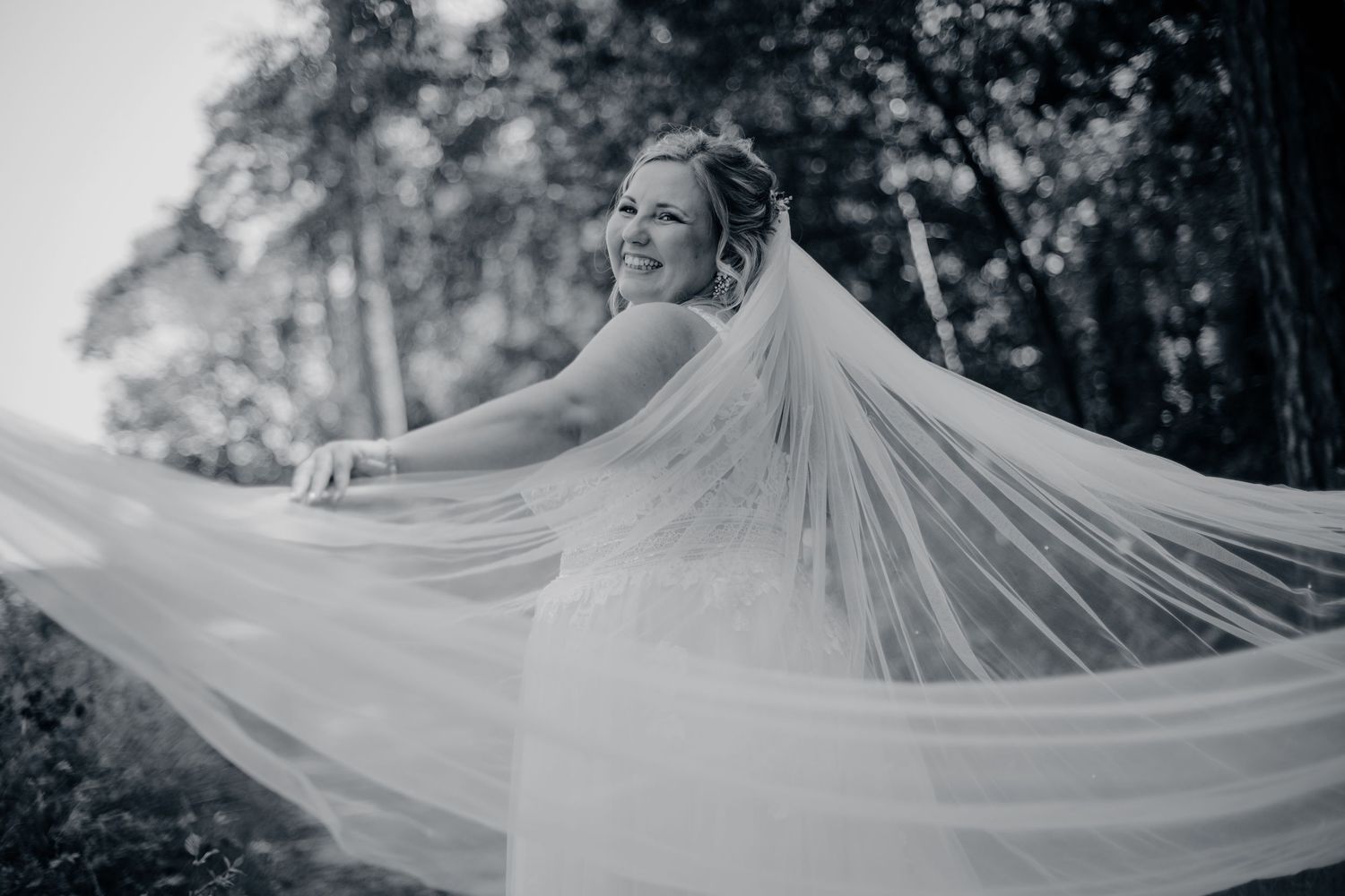 Zwart wit foto van bruid met sluier in bosrijke omgeving, artistieke bruidsfotografie in Brabant