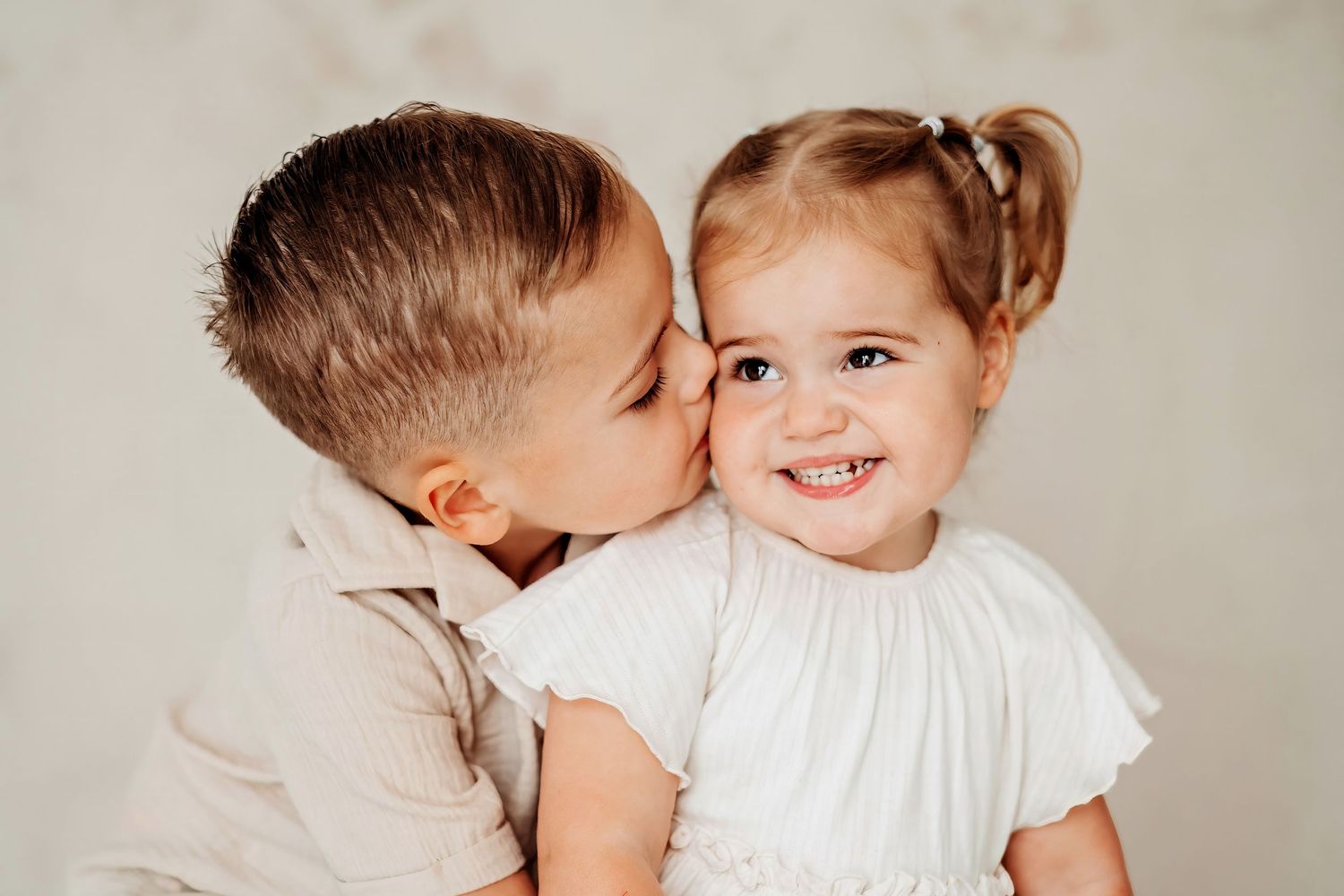 Broer en zus delen een liefdevol moment tijdens studioshoot in Vught, spontane kinderfotografie