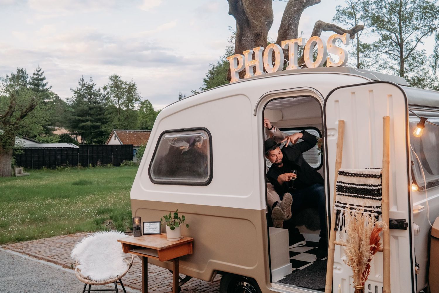 Retro photobooth camper van opgezet bij buitenbruiloft op schemering, bruidsfotografie Brabant