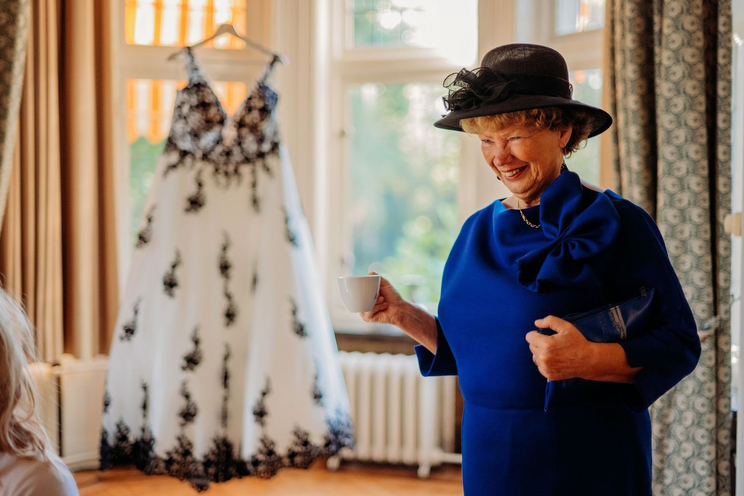 Persoon in blauw outfit deelt vrolijk moment in elegante interieur setting, portretfotografie Huize Bergen Vught, Brabant.