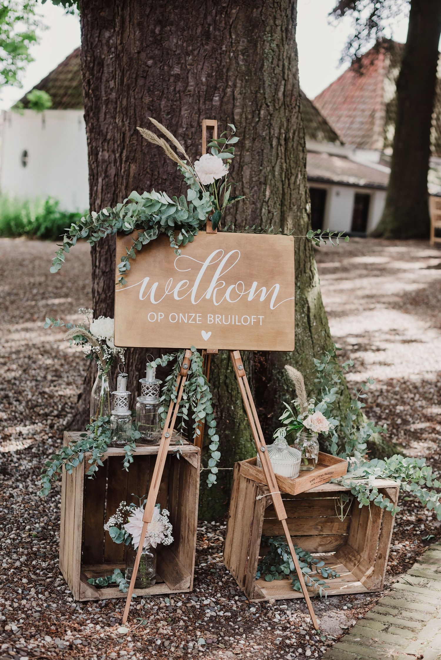 Rustieke houten bruiloftsbordjes met groen decor tegen bomen, bruidsfotografie Brabant