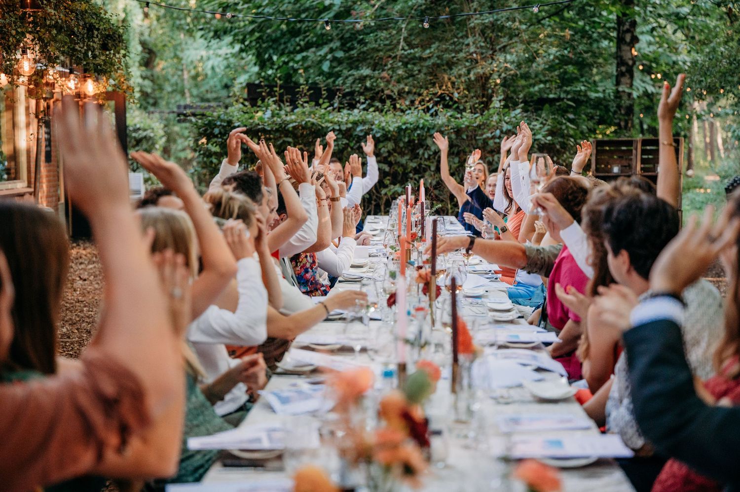 Bruiloftsgasten aan lange tafels vieren feest buiten, spontane bruidsfotografie bij Mr van Eijck Oisterwijk, Brabant.