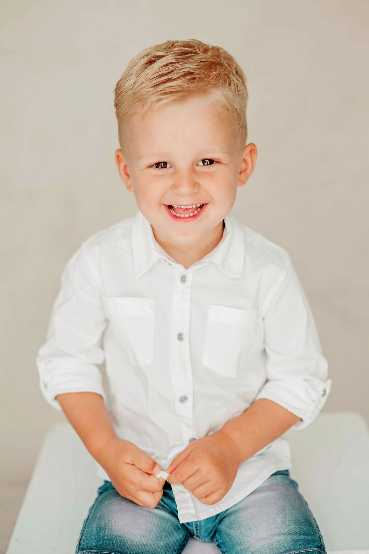 Jongen in studio met lichte kleding en neutrale achtergrond, professionele kinderfotografie Brabant