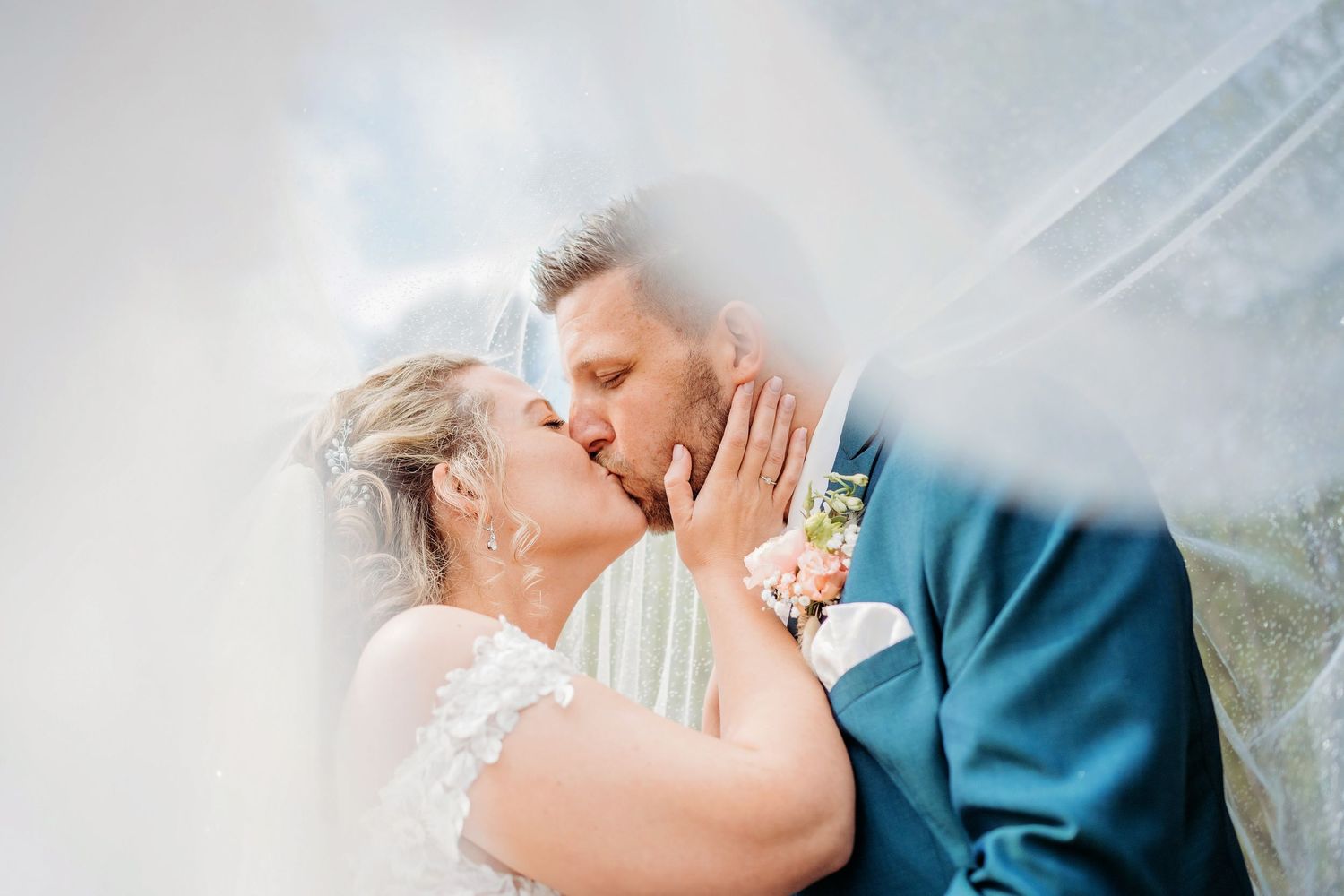 Bruidspaar deelt een liefdevolle kus bij raamlicht, romantische bruidsfotografie bij Mr van Eijck Oisterwijk, Brabant.