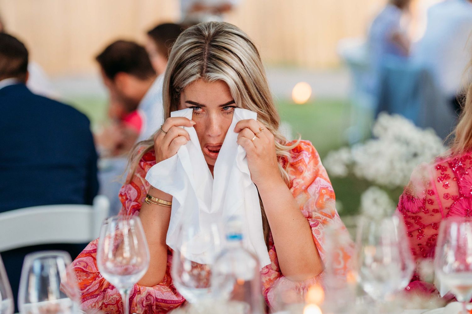 Gasten genieten van diner op elegant gedekte tafels met bloemen, bruiloftsfotografie Brabant.