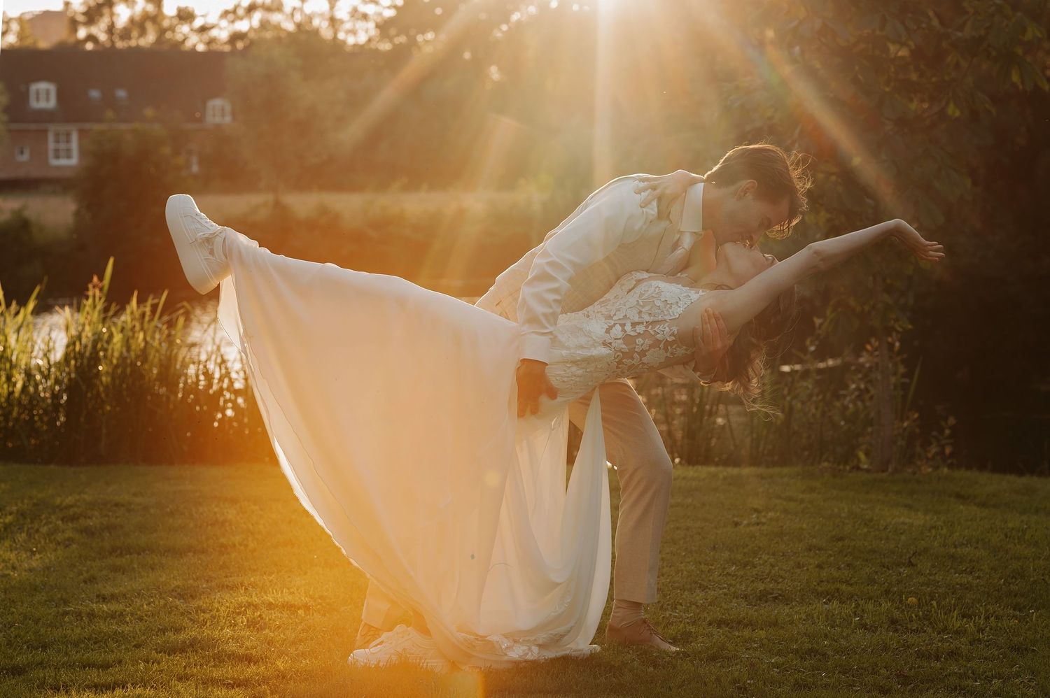 Couple sharing a romantic golden hour wedding dance outdoors, bride in flowing white gown, bathed in warm sunset light.