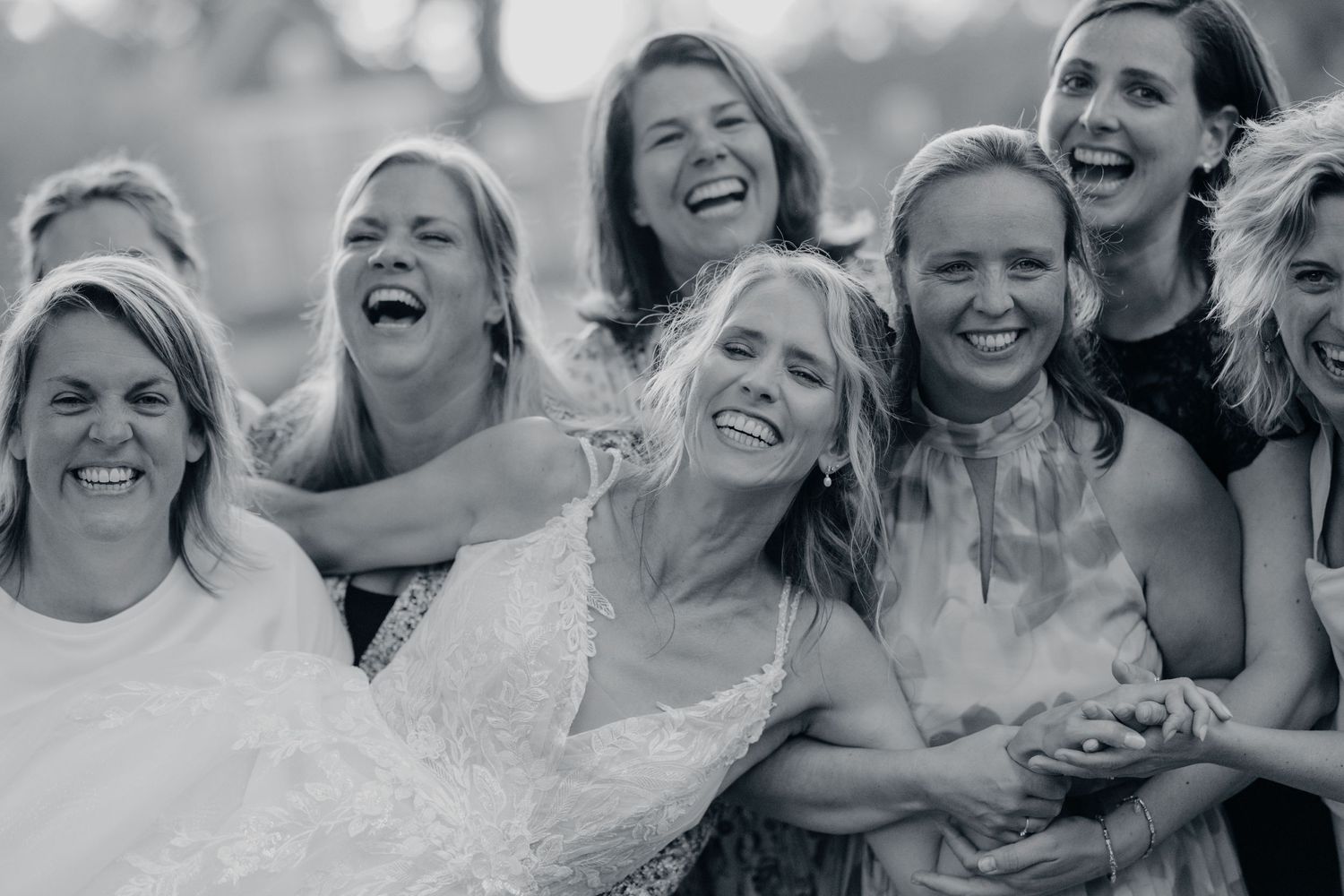 Bruidsfeest deelt candid lachen buiten in bijpassende outfits, bruidsfotografie Brabant