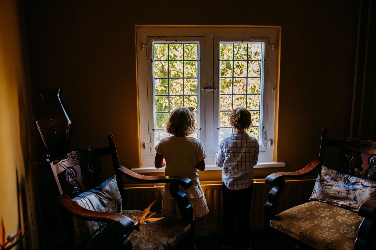 Silhouettes against bright window during wedding day preparations.