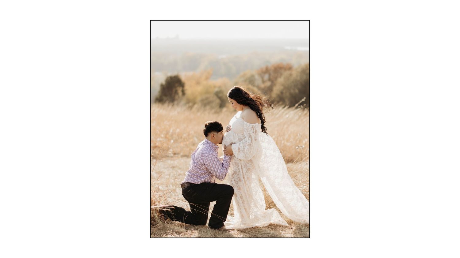 Romantic outdoor engagement photo showing a couple in formal attire on a golden grassy hillside.