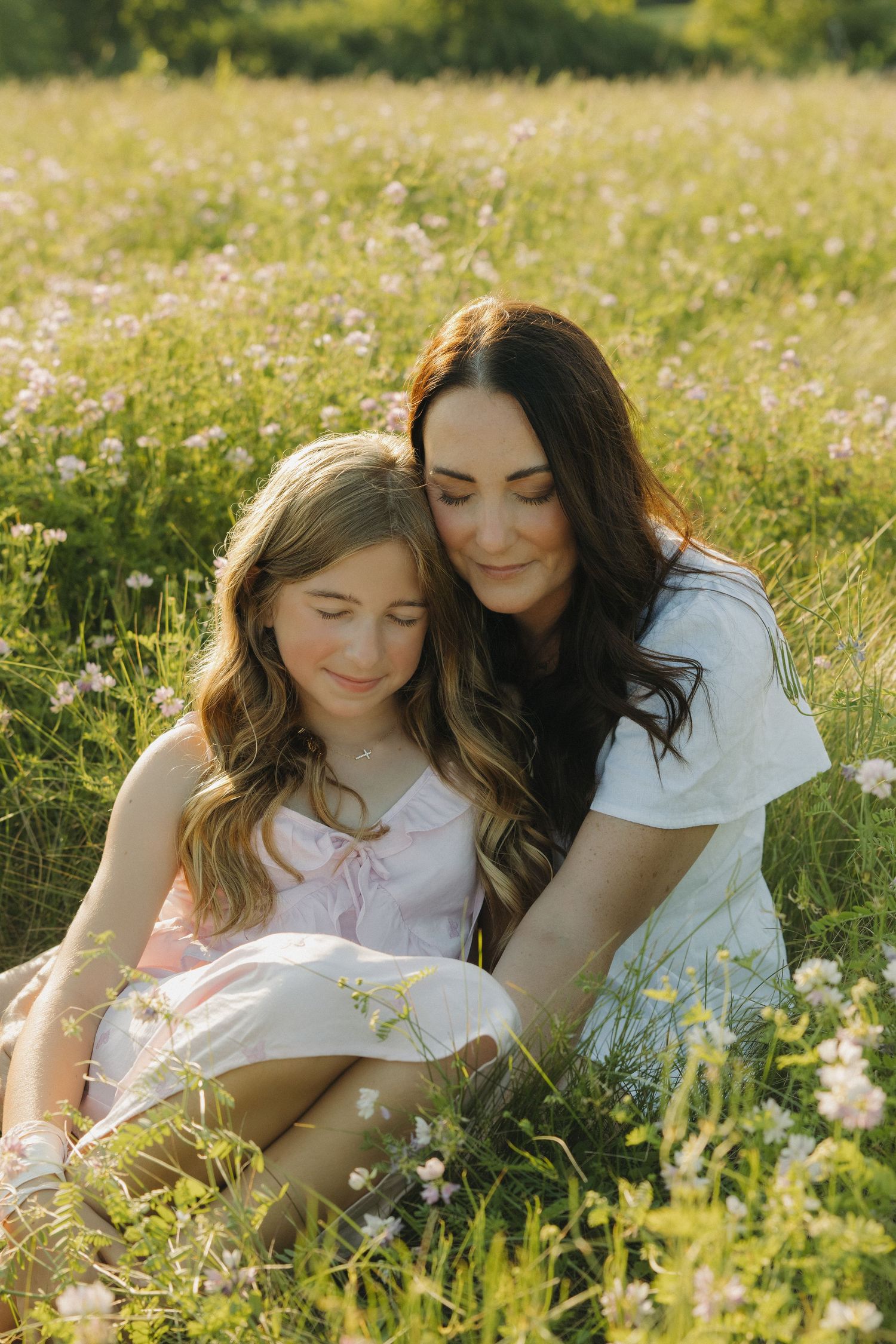 Two friends share a tender moment while relaxing in a sunny meadow filled with wildflowers on a summer afternoon.
