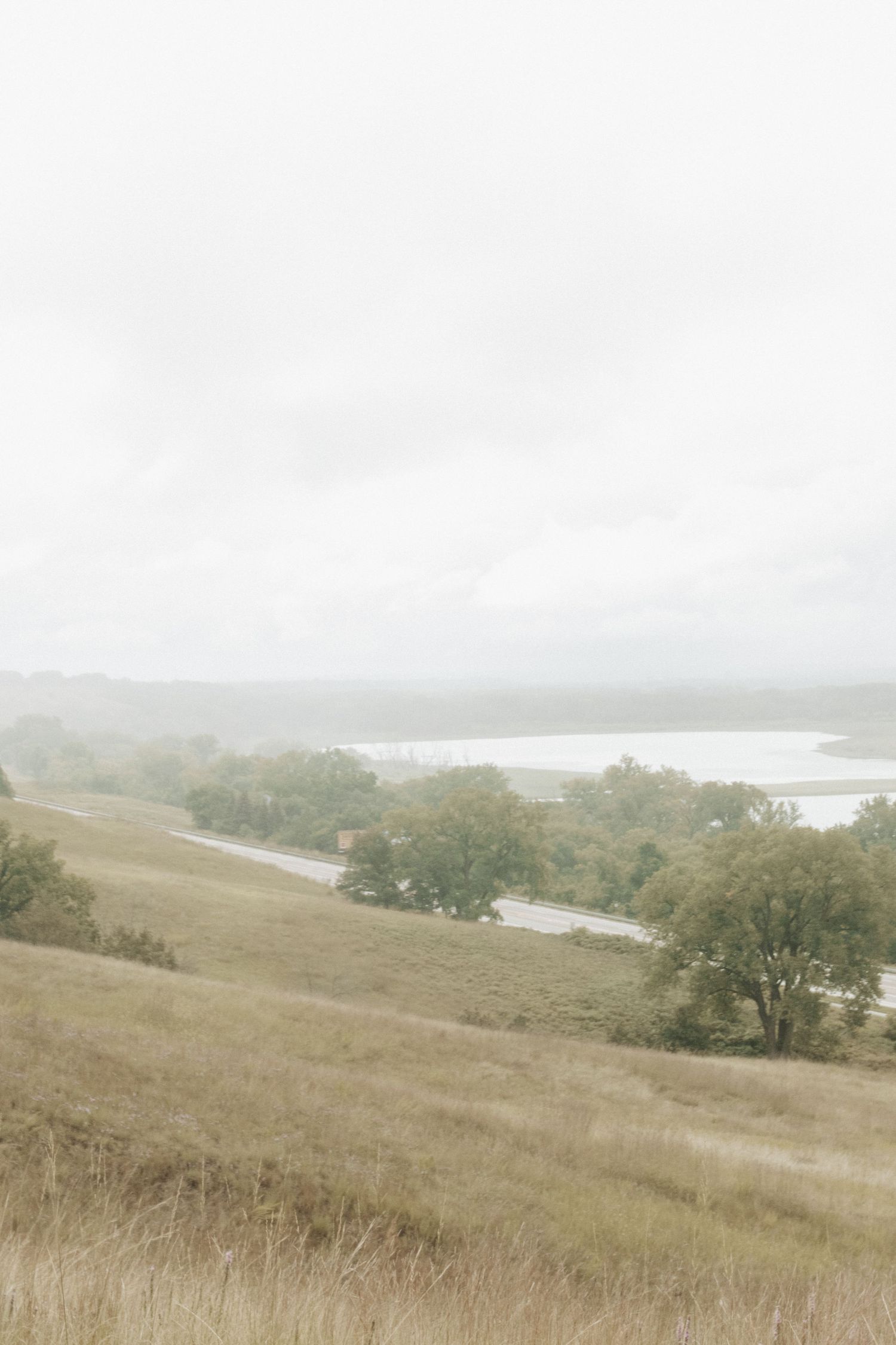 Rolling hills and lake landscape under cloudy sky with natural grasslands.
