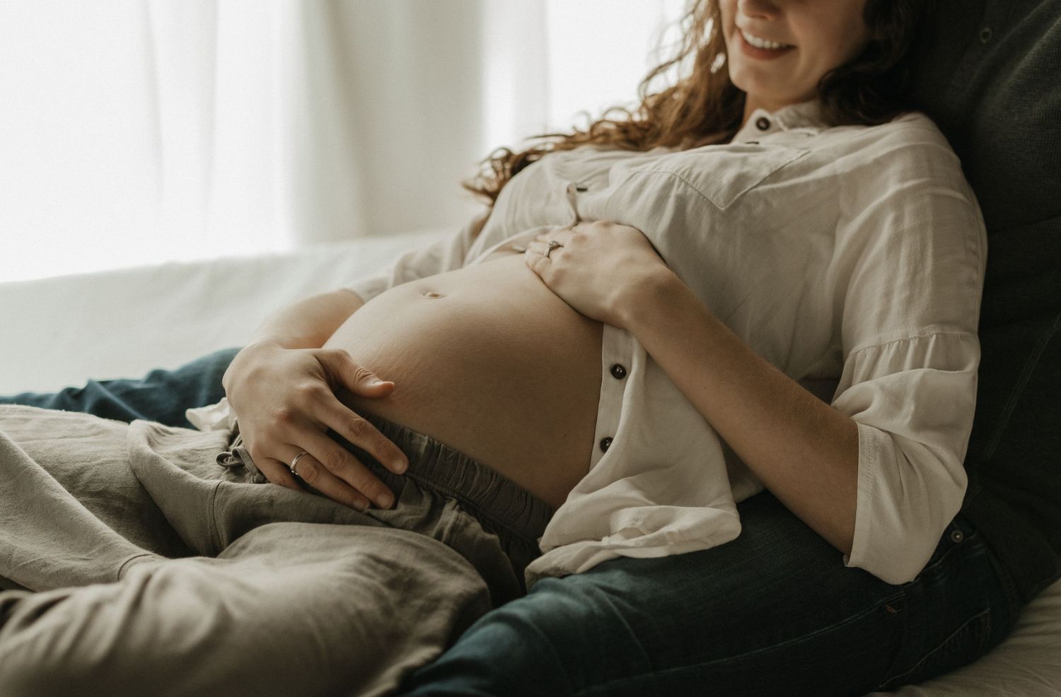 Intimate maternity photo showing an expectant mother resting in soft window light.