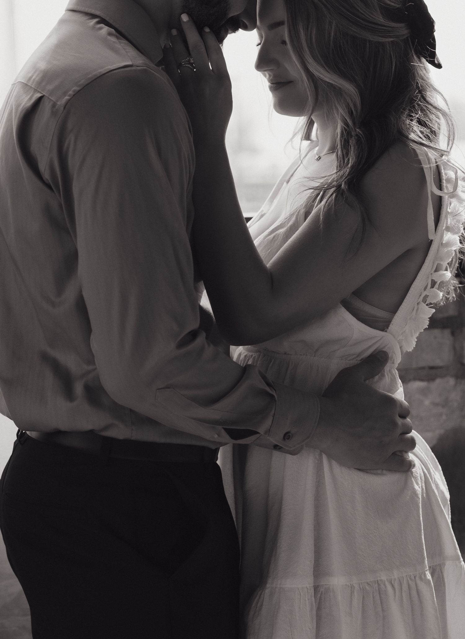 A romantic black and white photo of a couple embracing intimately in vintage-style clothing.
