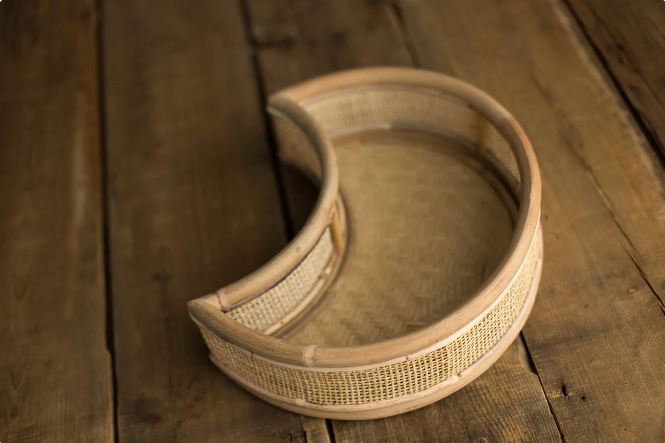 Crescent-shaped wooden tray with woven rattan detail on rustic dark wood surface.