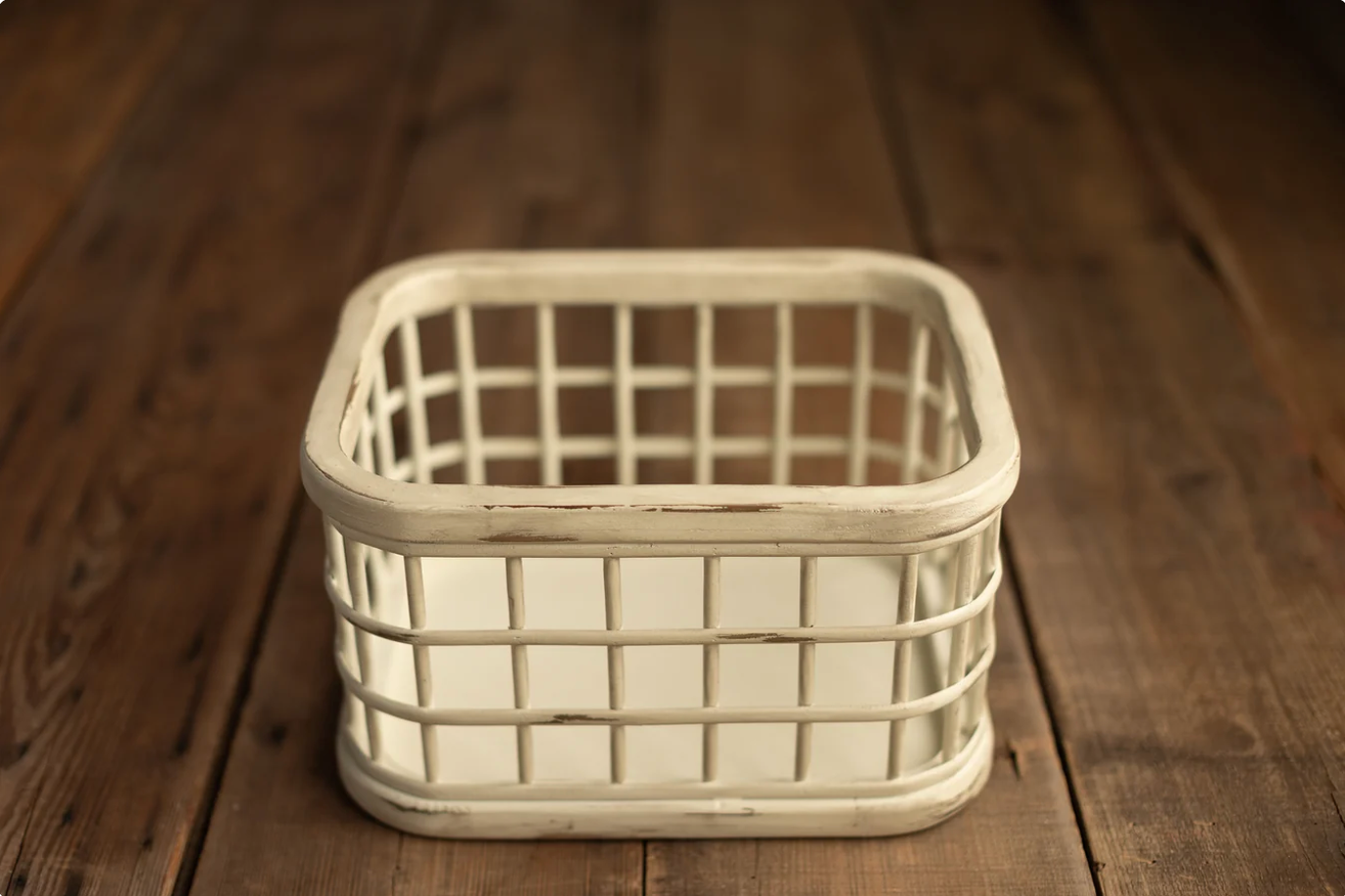 White distressed wooden basket with grid pattern sides sitting on rustic brown wood surface.