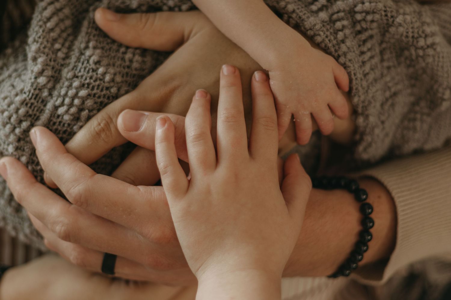 Close-up of family hands layered together, including baby feet, symbolizing love and family bonding.