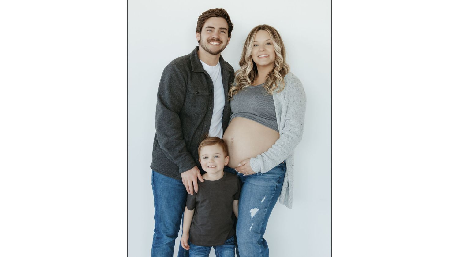 Studio portrait of a family group with a pregnant woman in casual clothing.