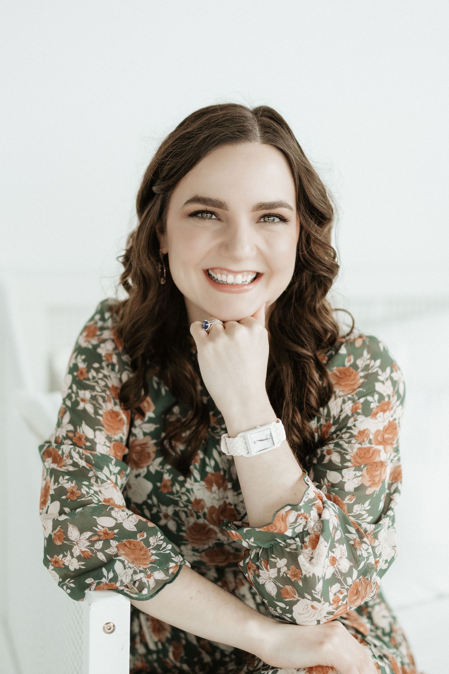 Portrait of someone in floral dress posing against bright white background.