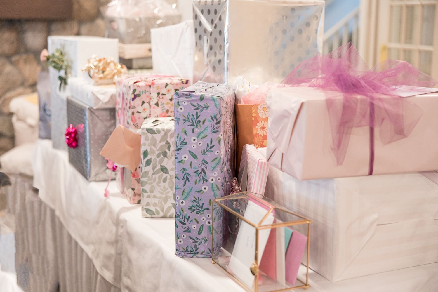Beautifully wrapped wedding or shower gifts in pastel colors arranged on a white tablecloth.