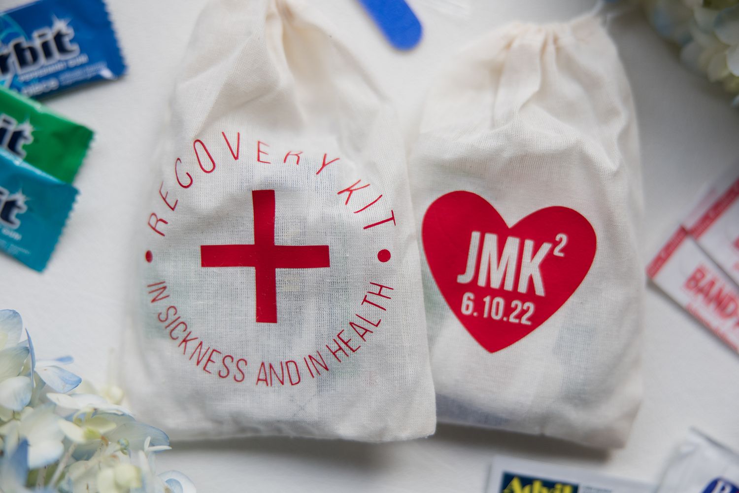 Close up of wedding welcome bags with red cross and heart logos on white fabric.