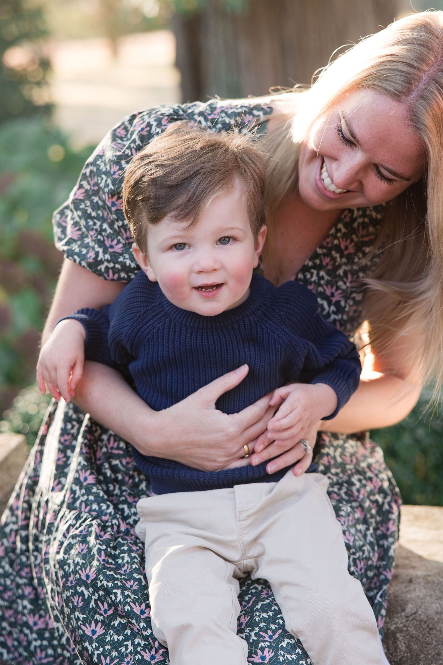 An intimate moment between parent and child laughing and playing together in a sunny outdoor setting.