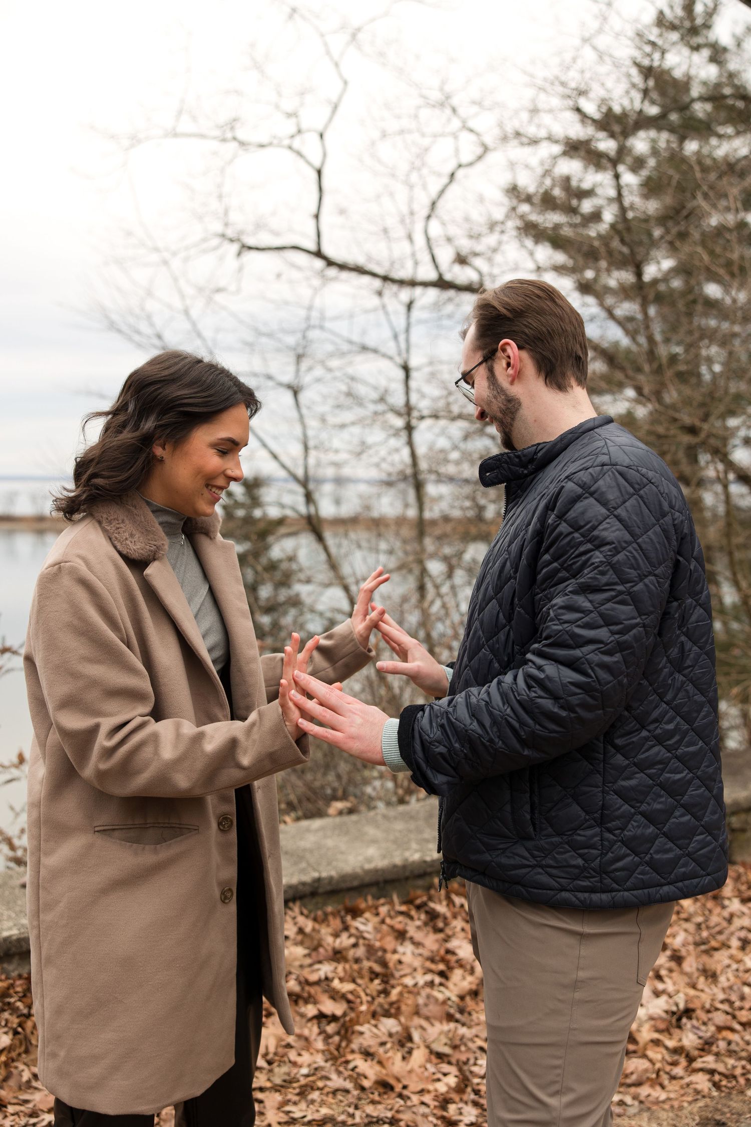 Two people examining a ring together in an outdoor lakeside setting.