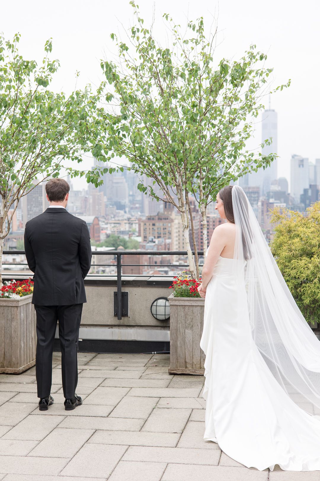 A couple shares their first look moment on a rooftop terrace overlooking the New York City skyline.