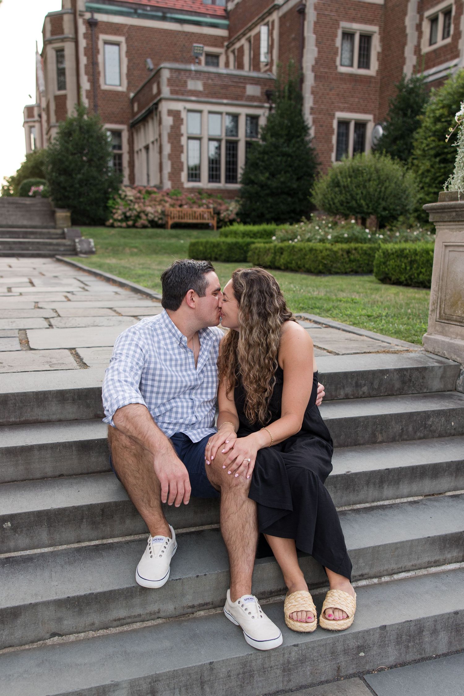A tender moment shared on stone steps with a brick mansion in the background.