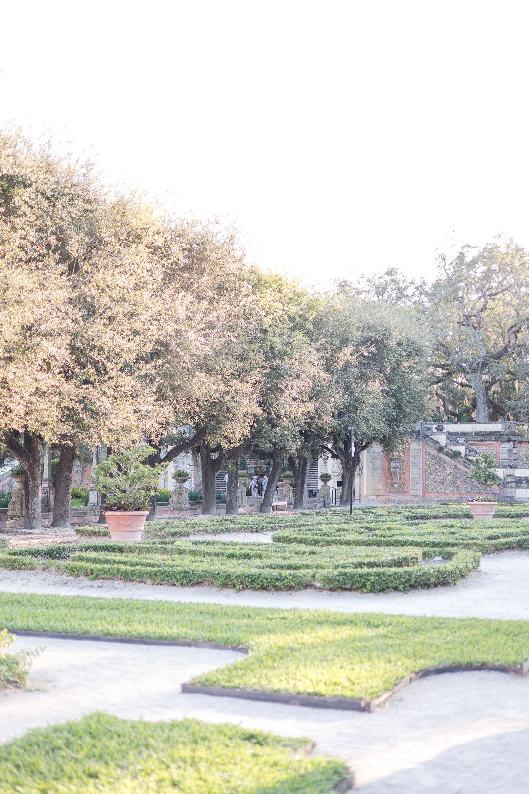 Geometric garden maze with manicured hedges and pathways surrounded by mature trees.