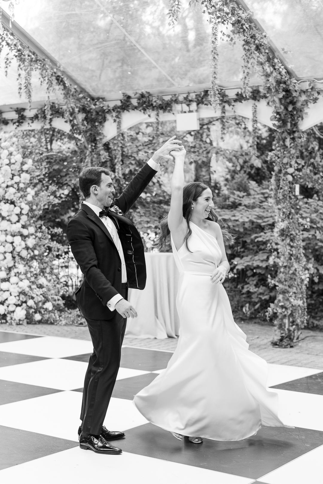 Dancing couple twirling on a checkered dance floor under a floral-decorated tent ceiling.
