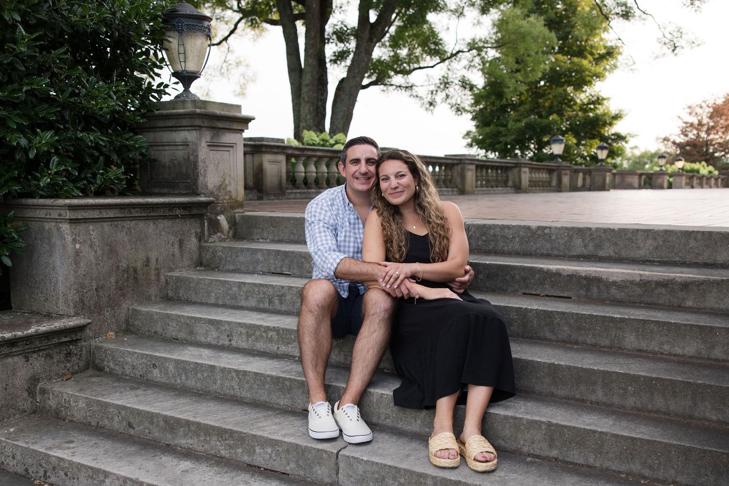 A couple poses casually on historic stone steps during an outdoor photoshoot.