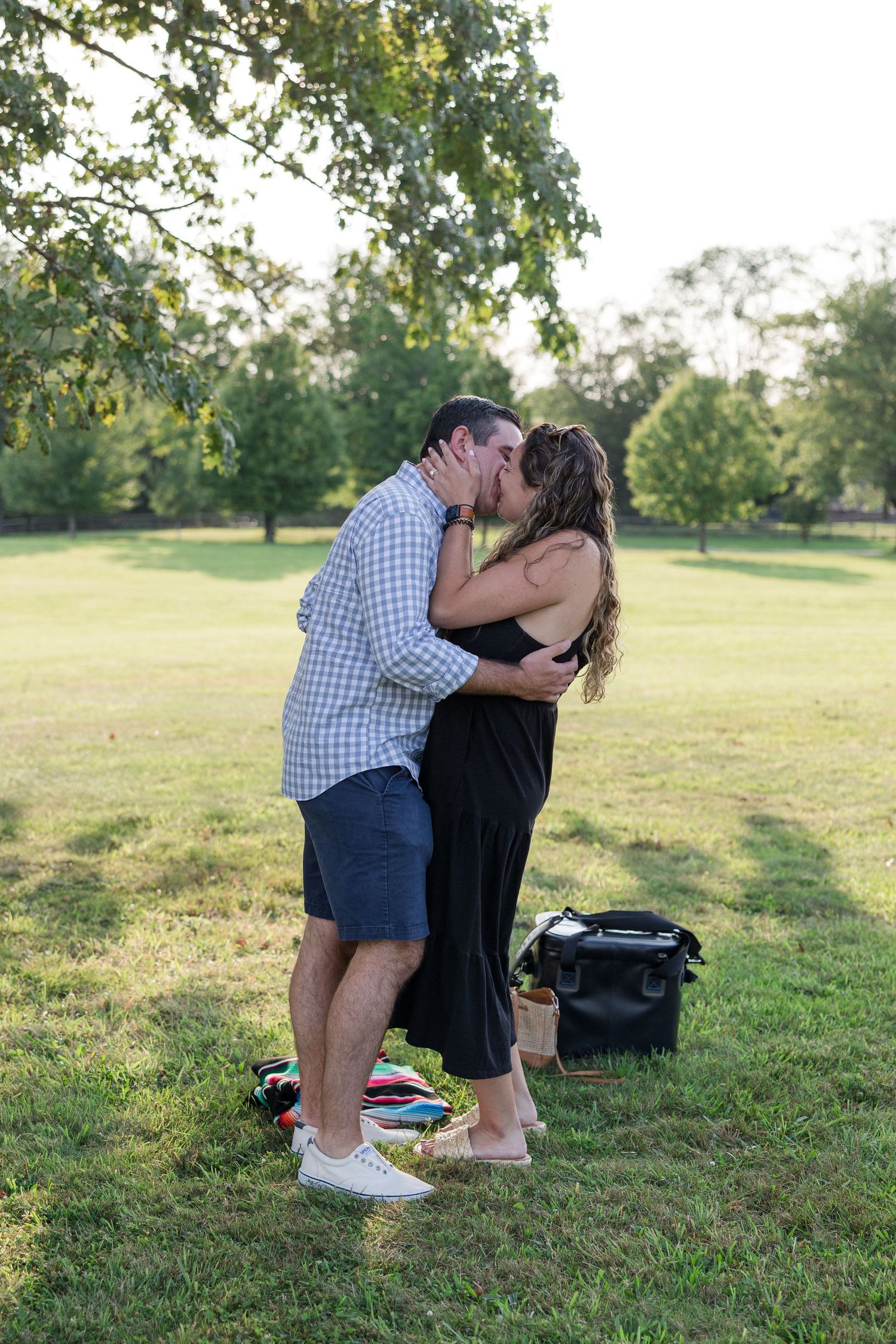 A romantic moment captured between two people in a park during golden hour.