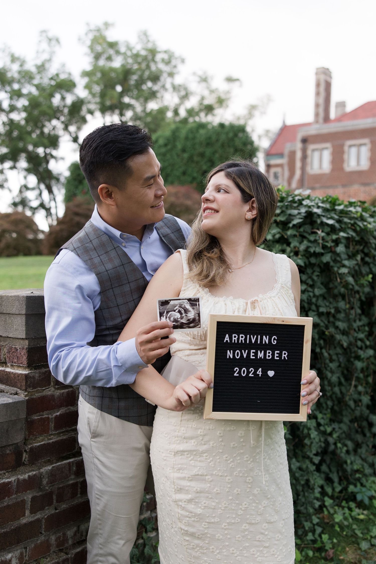 Couple holding ultrasound and letter board announcing November 2024 baby arrival.