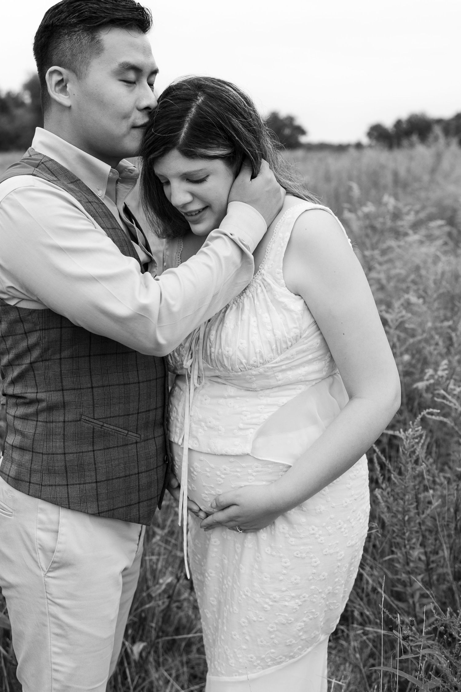 Romantic black and white portrait of couple sharing tender moment in outdoor field.